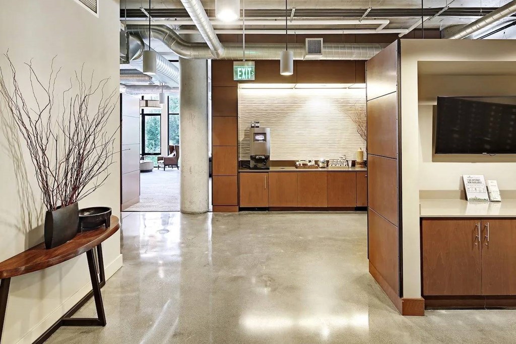A hallway with a bench, a plant, and a reception desk.