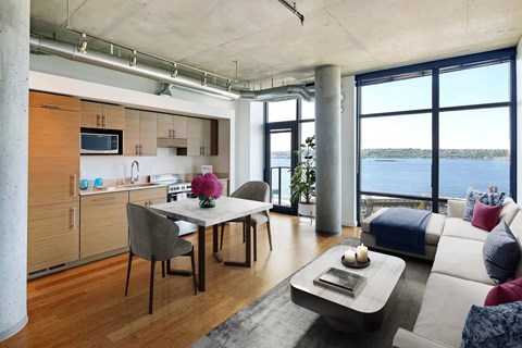 A modern kitchen with a dining table and a couch with a view of the water.