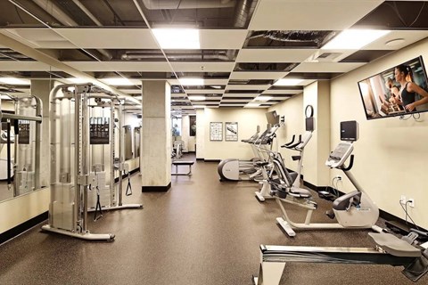 A gym with a variety of equipment including treadmills, weights, and exercise machines.