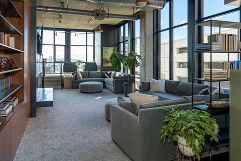 A modern living room with a grey sofa and a large window.