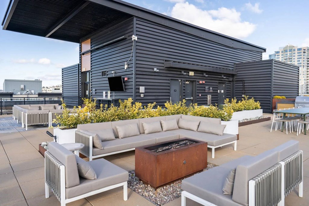 A patio with a white couch and a fire pit.