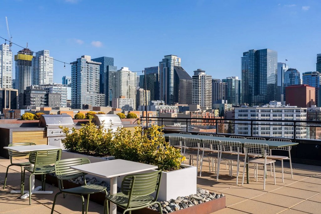 A rooftop patio with a table and chairs overlooking a city skyline.