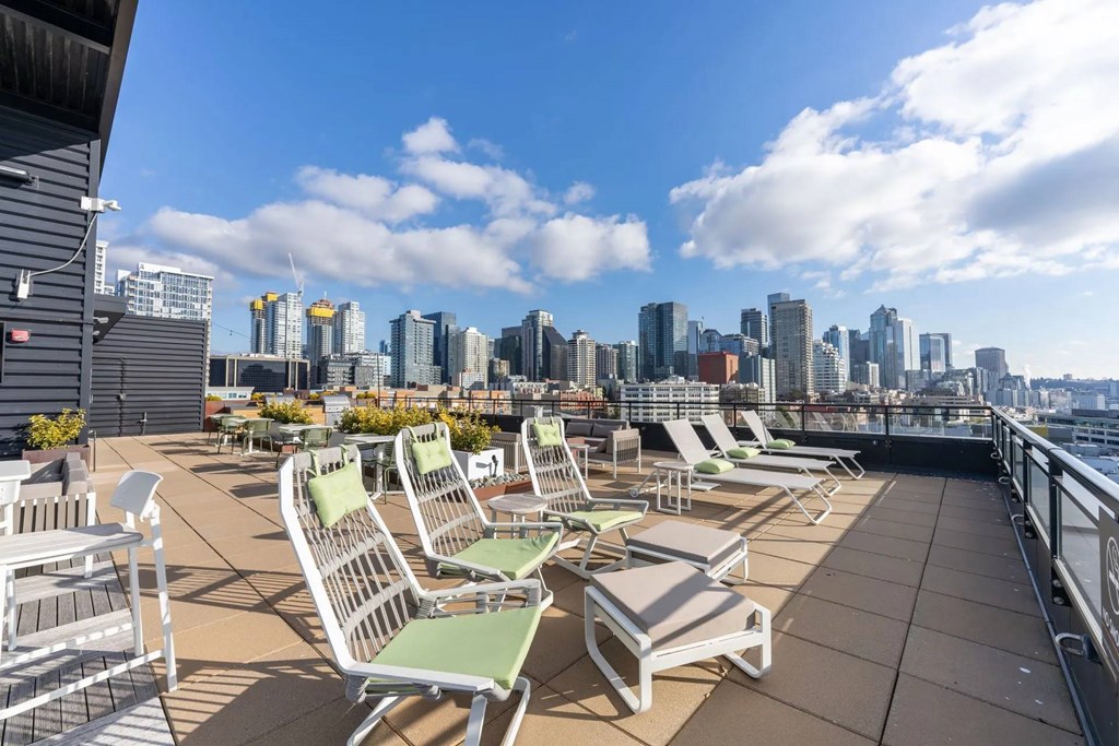 A rooftop patio with several chairs and a view of a city skyline.