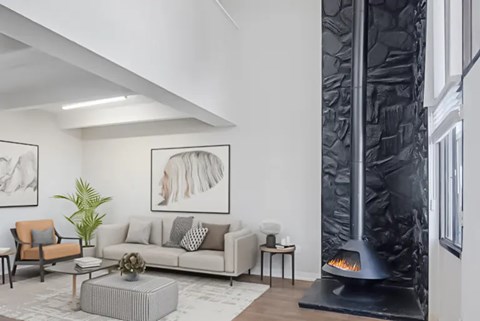 A modern living room with a grey sofa, a coffee table, a fireplace, and a potted plant.