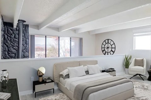 A bedroom with a large bed, a chair, and a clock on the wall.