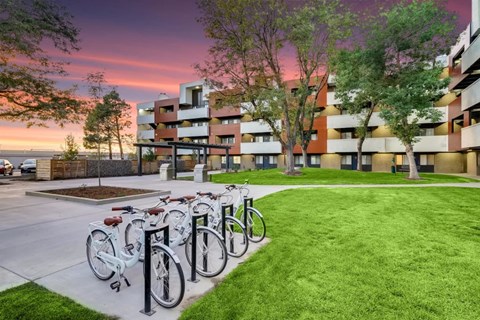 A row of bicycles are parked on a sidewalk in front of a building.