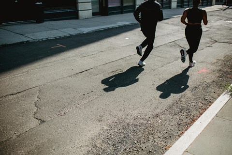 Two people running on a street.