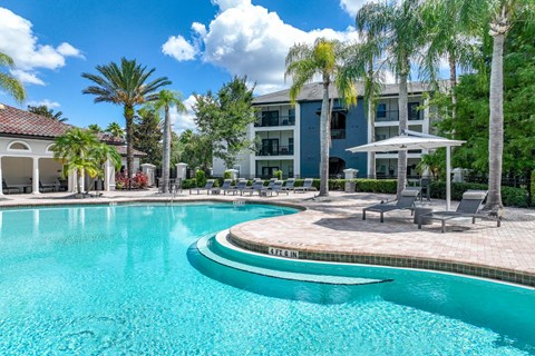 a pool with palm trees at Verano apartments