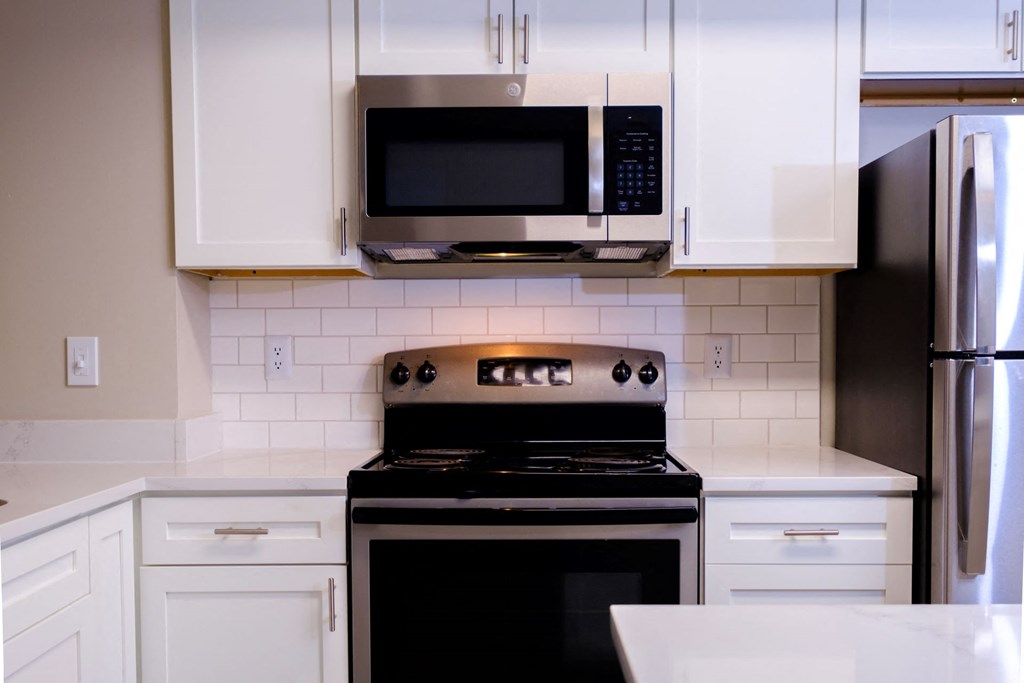 a kitchen with white cabinets and stainless appliances