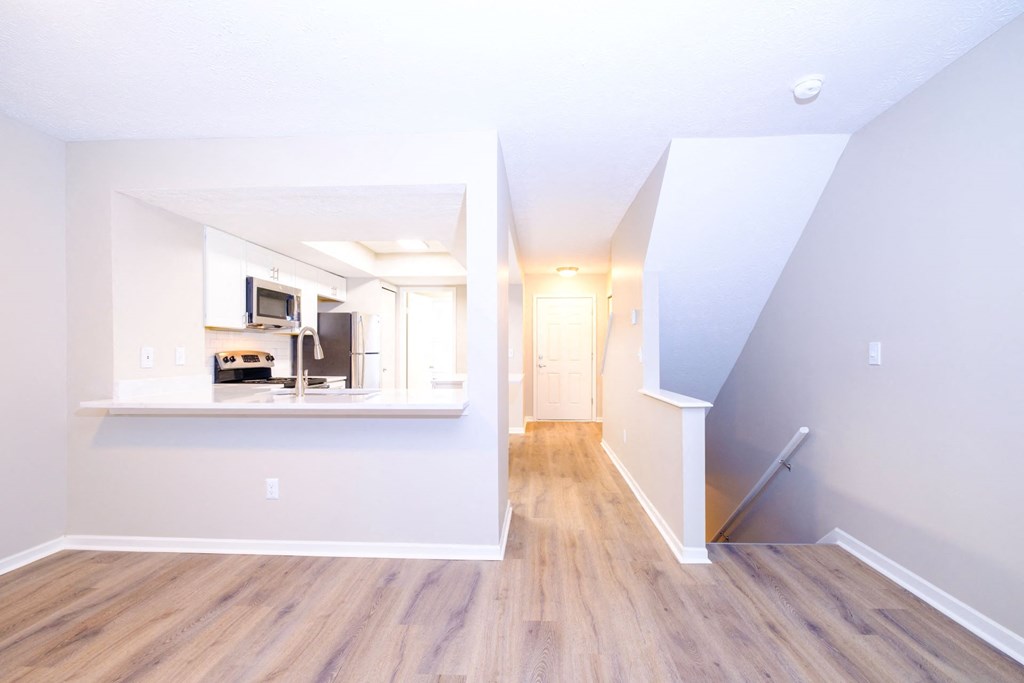 a spacious living area with hardwood floors and a kitchen in the background