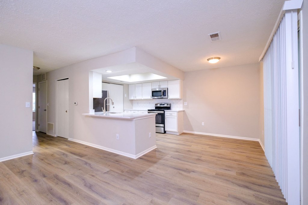 a spacious living room with a kitchen in the background