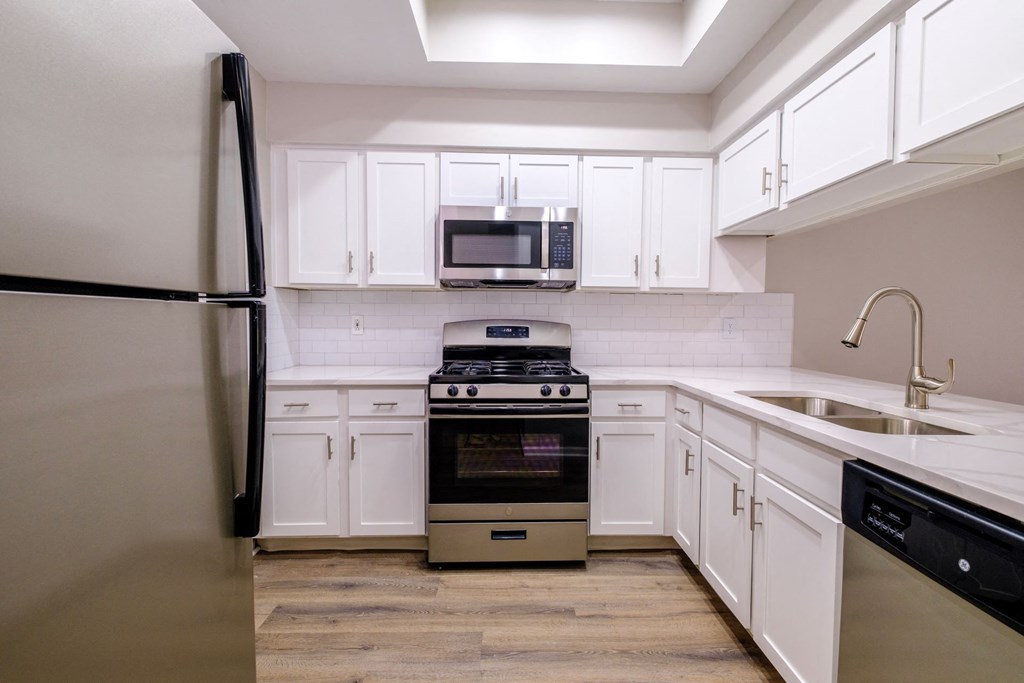 a kitchen with white cabinets and stainless steel appliances