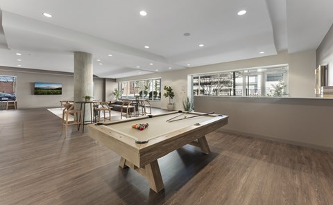 A pool table is in the middle of a room with wood flooring.