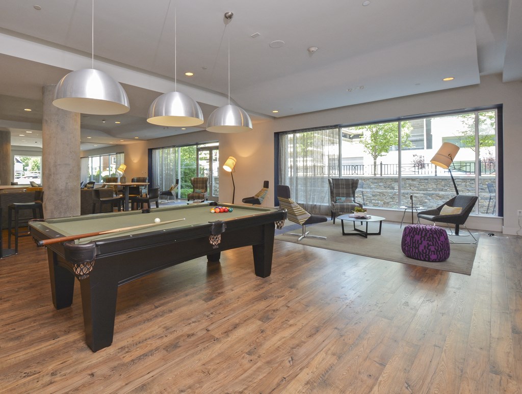 Resident lounge with hardwood flooring, pool table and soft seating on rug in background