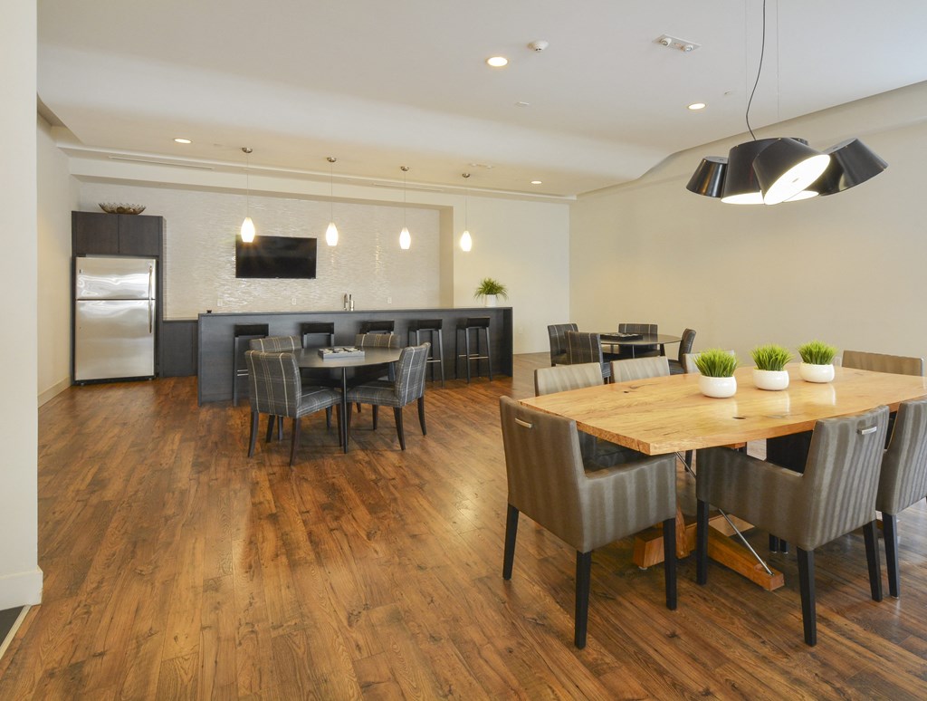 Resident kitchen with long island, refrigerator, wall-mounted TV and multiple dining tables
