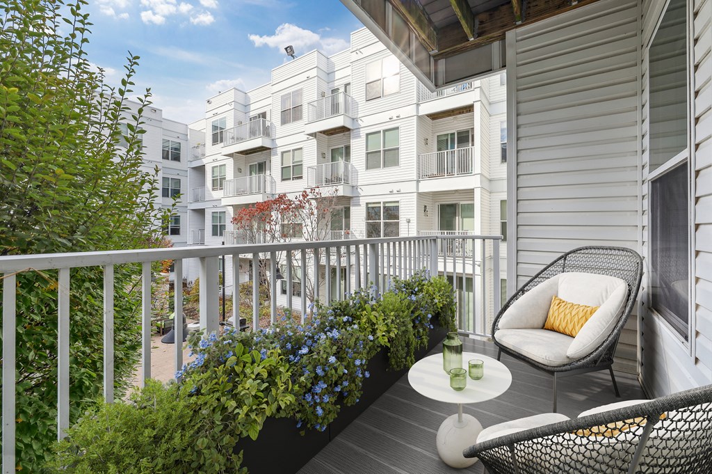 a balcony with two chairs and a table and some plants