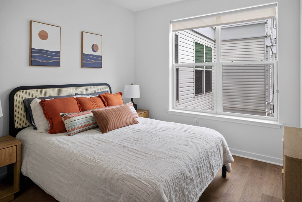 A bedroom with a bed, nightstand, and two framed pictures on the wall.