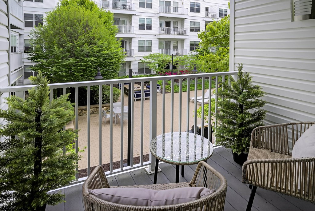 A balcony with a table and chairs overlooking a courtyard.