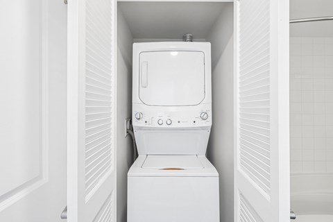 A white washing machine is sitting in a small space.