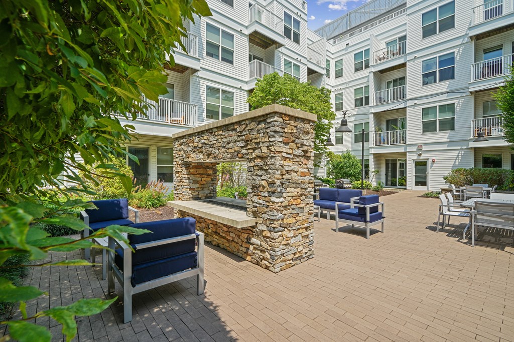 an outdoor patio with a stone fireplace and seating area at an apartment building