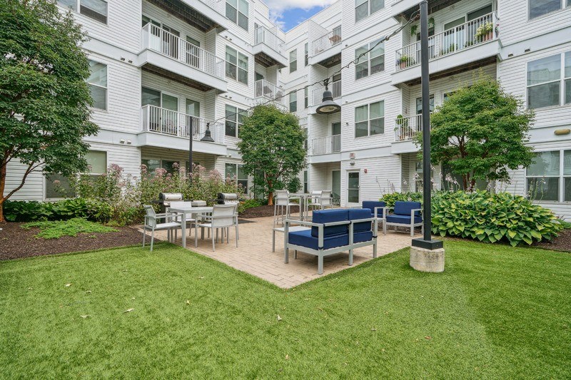 a courtyard with tables and chairs in front of an apartment building