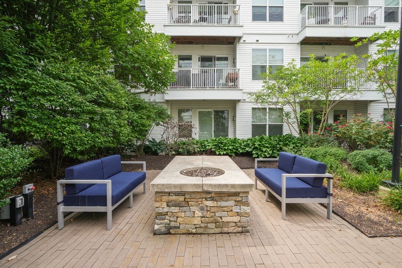 a fire pit on a brick patio with blue chairs