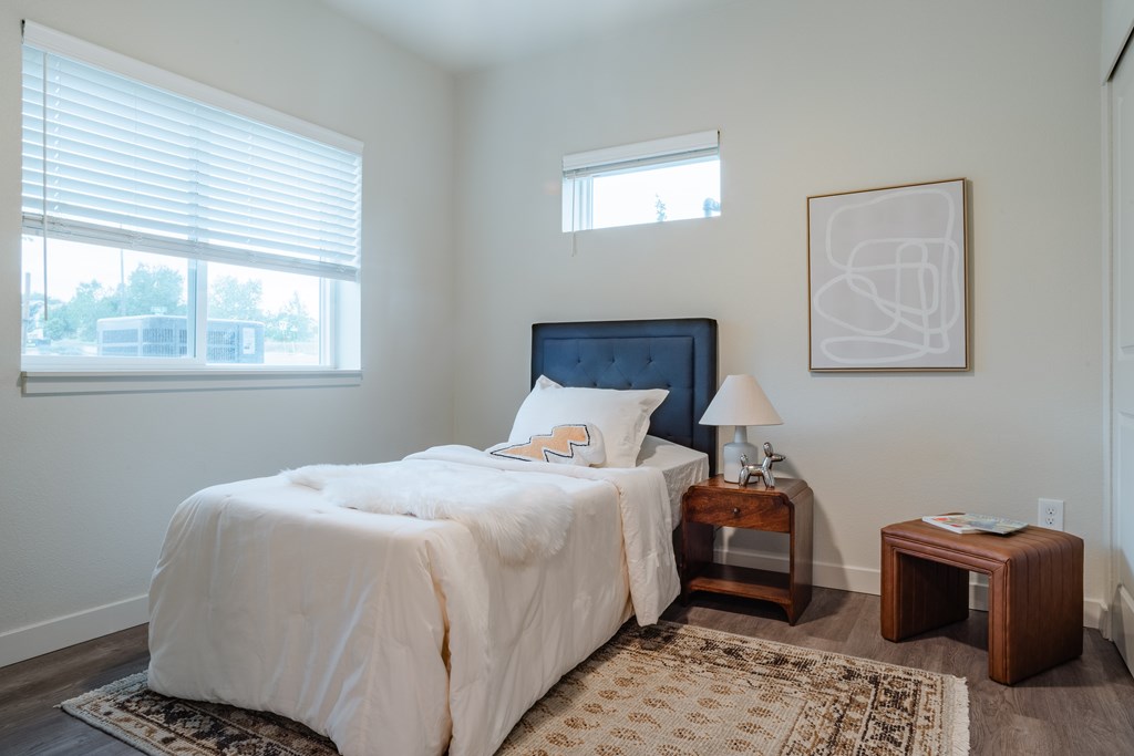 A bedroom with a large bed and a window with blinds.