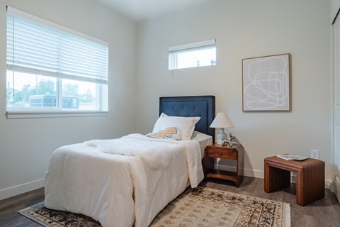 A bedroom with a large bed and a window with blinds.