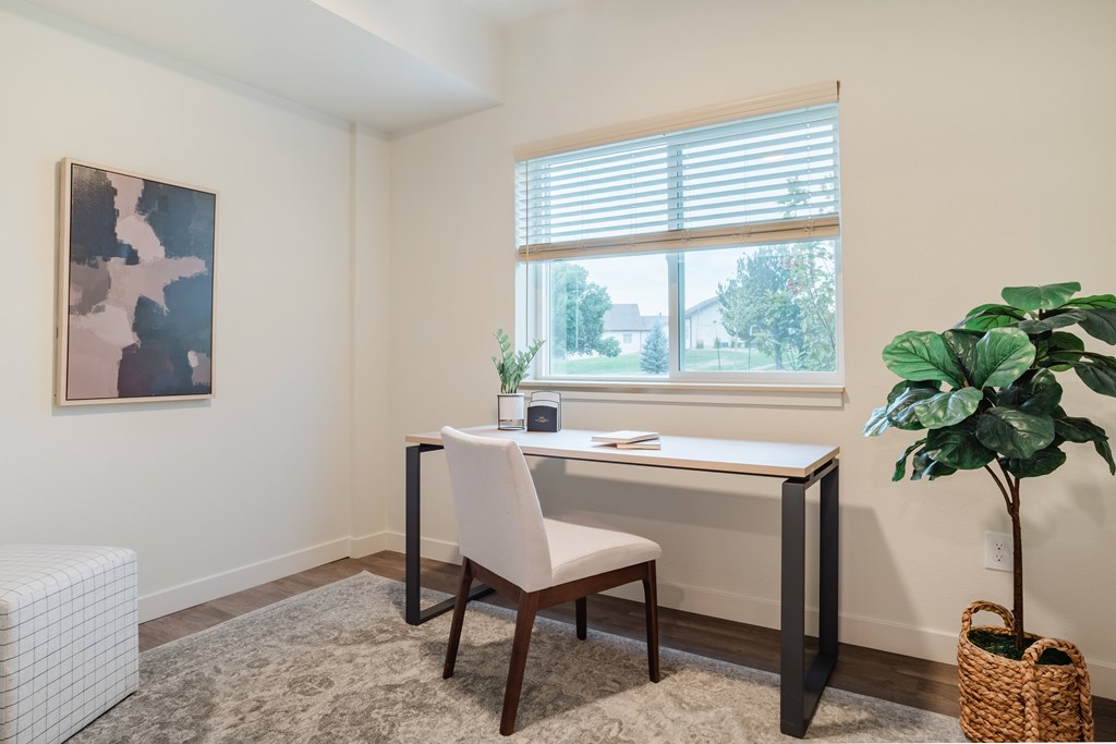 A room with a desk, chair, and a painting on the wall.