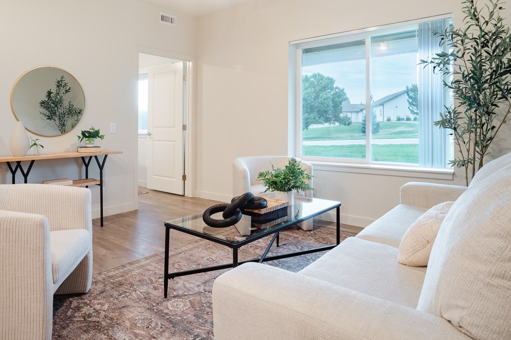 A living room with a white couch and a glass coffee table.