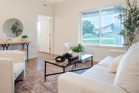 A living room with a white couch and a glass coffee table.
