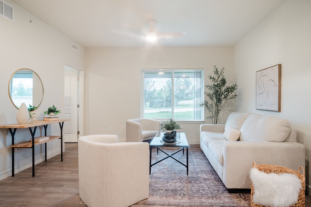 A living room with a white couch, a white chair, and a white ottoman.