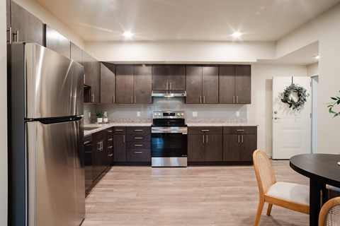 A modern kitchen with a stainless steel refrigerator and wooden flooring.