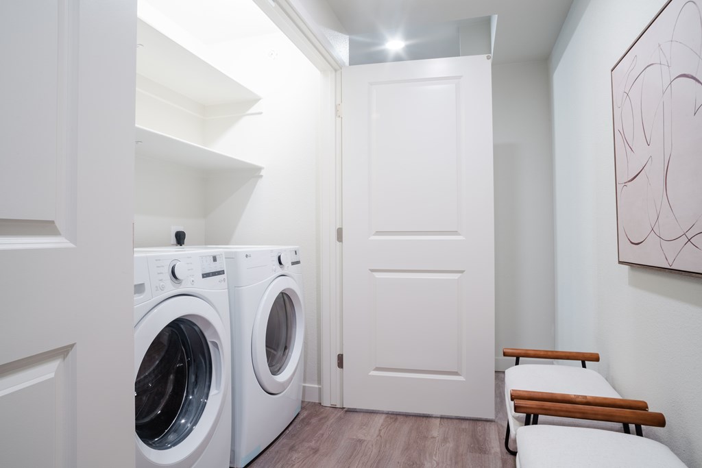 A laundry room with a washer and dryer and a bench.