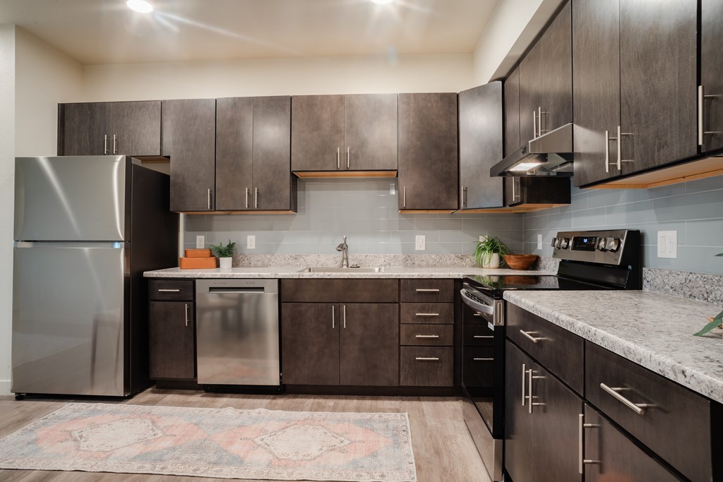 A kitchen with dark brown cabinets and a patterned rug on the floor.