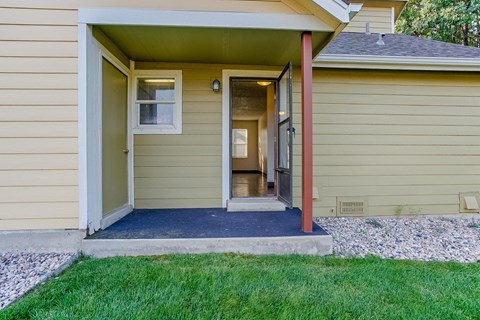 the front porch of a yellow house with a porch swing