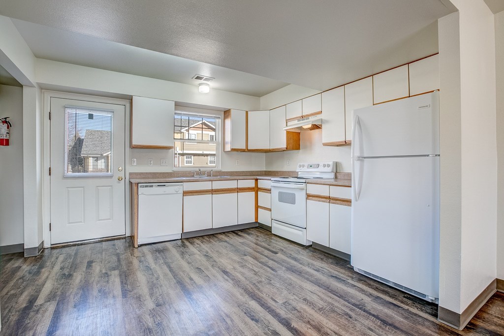 A kitchen with white appliances and wooden floors.