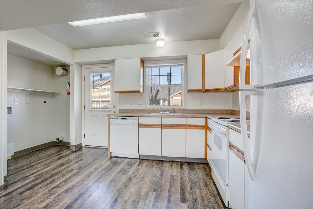 A kitchen with white cabinets and a wooden floor.