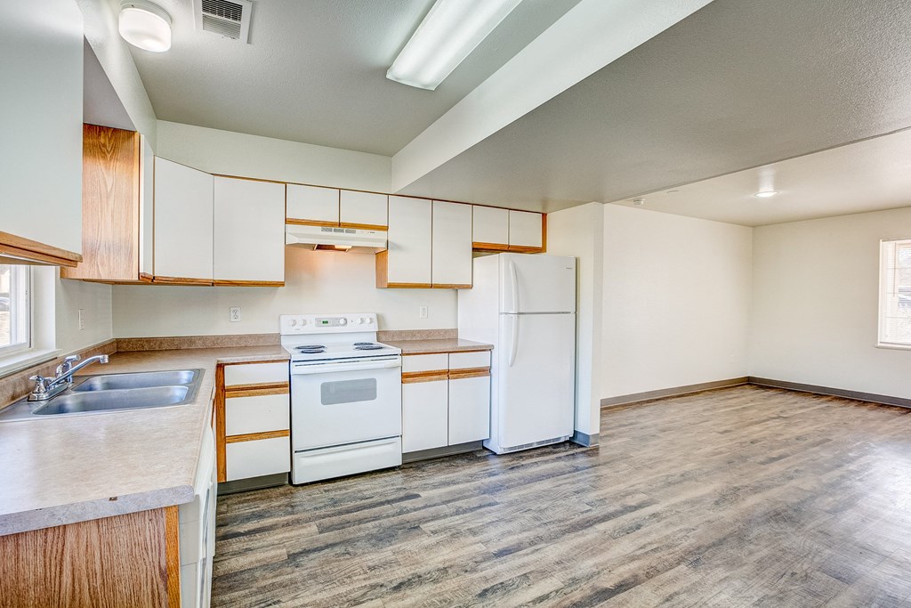 A kitchen with white appliances and wooden cabinets.