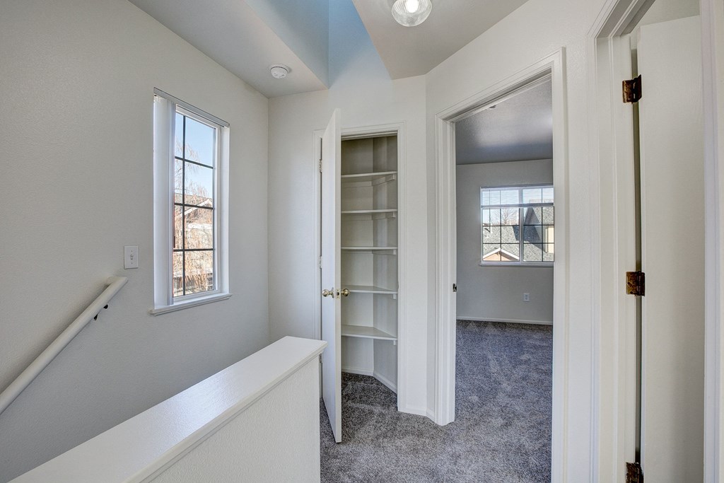A white hallway with a window and a door leading to another room.