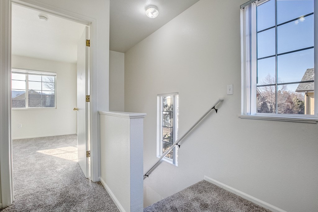 A white room with a staircase leading to another room.