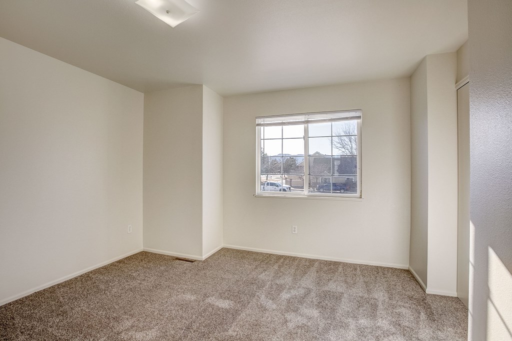 A room with a carpeted floor and a window.