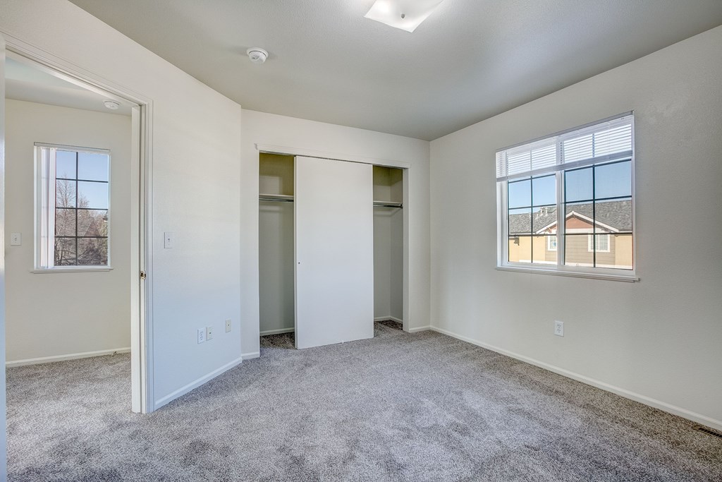 A spacious empty room with a carpeted floor and a window.