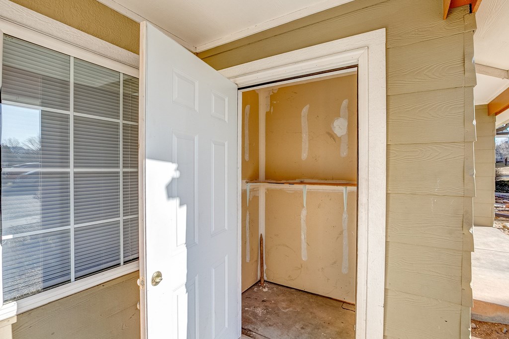 A white door is open to a room with a window and a wall.