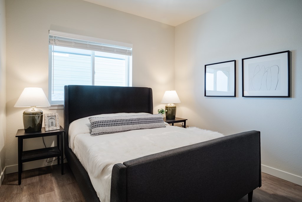 A bedroom with a large bed and two lamps on side tables.