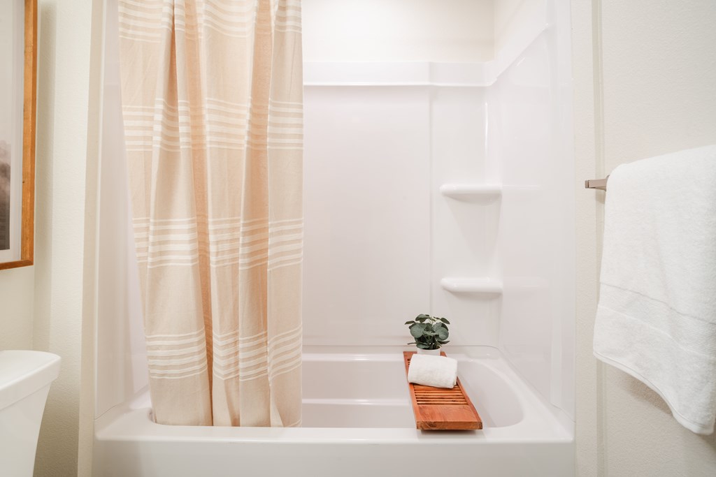 A white bathroom with a white tub and a white towel.