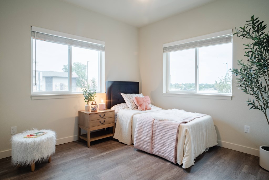 A bedroom with a bed, nightstand, and window.