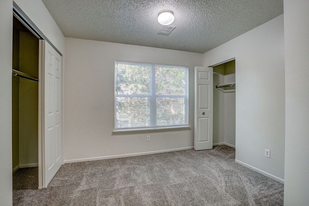 an empty room with a large window and a closet