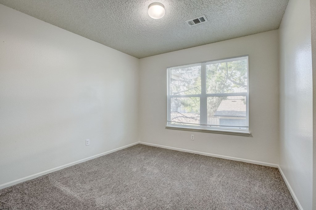 an empty living room with a window and carpet