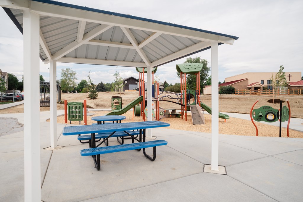A playground with a picnic table under a shelter.